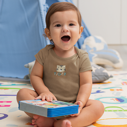 A smiling baby boy sitting on the floor, holding a book and looking at the camera.