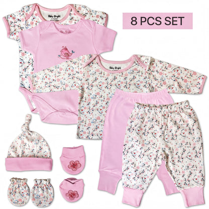 A set of baby clothing items, including a pink onesie, pants, a hat, and booties, arranged on a white background.