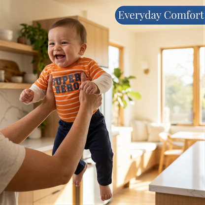 A smiling baby wearing an orange and blue striped shirt is being held up by someone in a kitchen.